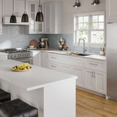 a kitchen with white cabinets and an island in the middle is seen from across the room