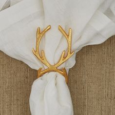 a napkin holder with a gold deer head on it, sitting on top of a white cloth