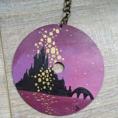 a purple and gold painted wooden disc with a castle on the top, surrounded by stars