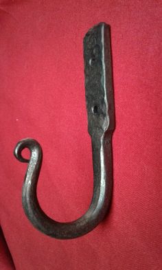 an old iron hook hanging on a red shirt with the handle extended to it's side