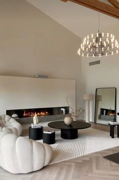 a living room with white furniture and a chandelier hanging from the ceiling above it