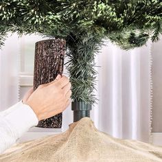 a person is placing pine cones on the top of a christmas tree to decorate it