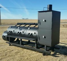 a large black machine sitting on top of a dry grass field