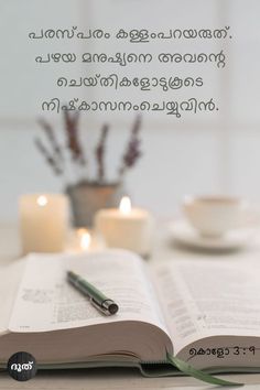 an open book sitting on top of a table next to two candles and a cup