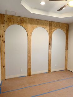 an empty room with three arched windows and no insulation