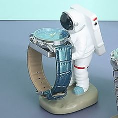 an astronaut watch is on display next to other watches and figurines that are sitting on a table