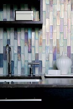 a kitchen counter with a sink and some shelves above it that have glass tiles on the backsplash