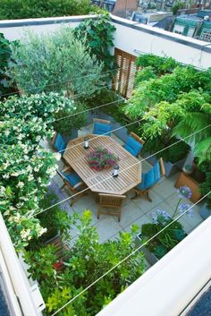 an aerial view of a table and chairs surrounded by greenery on the roof terrace