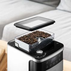 an automatic coffee maker with two trays on the top and one being filled with coffee beans