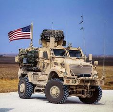 an army truck parked on the side of the road with flags flying in the background