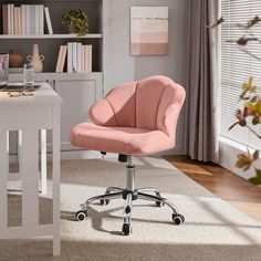 a pink office chair sitting on top of a wooden floor next to a white desk