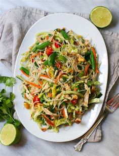 a white plate topped with salad next to limes