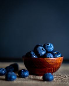 a wooden bowl filled with blueberries on top of a table