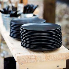 black plates stacked on top of each other on a wooden table with utensils in the background