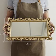 a person holding a gold framed mirror in their hands