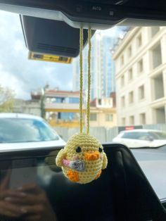 a crocheted bird hanging from the dashboard of a car