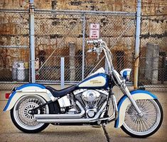 a blue and white motorcycle parked in front of a fence