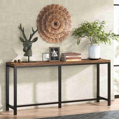 a wooden table topped with two vases next to a metal deer head on top of a wall