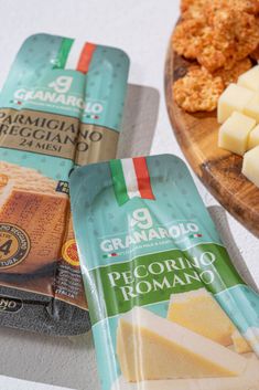 three packages of cheese sitting on top of a wooden plate next to other food items