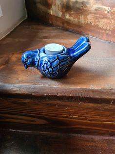 a blue bird candle holder sitting on top of a wooden table