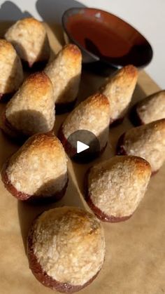 several pastries sitting on top of a piece of brown paper next to a spoon