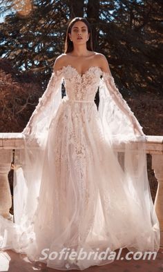 a woman in a wedding dress with long sleeves and an open - back gown is posing for the camera