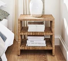 a stack of books sitting on top of a wooden table next to a white vase