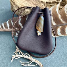 a brown leather purse with a stone bead hanging from it's side on a blue carpeted floor