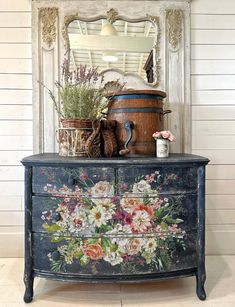 an old dresser with flowers painted on it and a mirror in the corner behind it