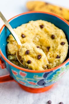 banana coconut flour mug cake in a blue and orange bowl with a spoon sticking out of it