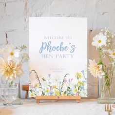 a welcome sign with flowers in vases on a table