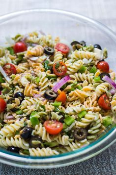 a glass bowl filled with pasta salad on top of a table