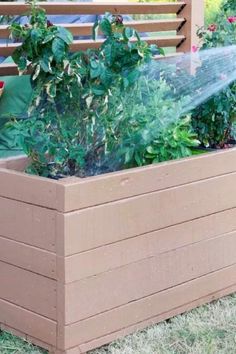 a garden box filled with plants and water sprinkles on the side of it