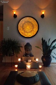 a buddha statue sitting on top of a wooden floor next to potted plants and candles