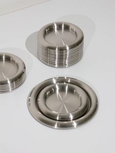 three metal plates sitting on top of a white counter