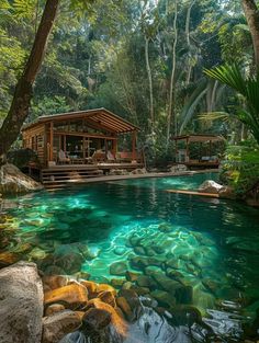 an outdoor swimming pool surrounded by trees and rocks with clear blue water in the foreground