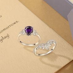 two silver rings with an amethyst purple stone in the middle on top of a card