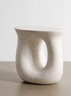 a white vase sitting on top of a table