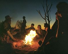 a group of people sitting around a campfire