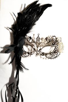 This is gorgeous gold masquerade mask that I just added to the large variety of different designs of metal masks and lace embroidered masks. This mask is a metal gold mask decorated with shimmered white rhinestones to enhance the design of the mask and the facial features This mask has a mask handle and decorated with a black flower and gorgeous black rooster feathers! I hope you love this mask! If you wish this mask to be without a stick please feel free to leave a note in the order that you wi Gold Gothic Masquerade Mask For Carnival, Gothic Gold Masquerade Mask For Carnival, Elegant Feathered Masquerade Mask For Mardi Gras, Elegant Feathered Masquerade Mask, Elegant Feathered Eye Mask For Masquerade, Gold Gothic Masquerade Mask For Party, Elegant Eye Mask For Theater, Elegant Theater Eye Mask, Elegant Feathered Masquerade Mask For Costume Party