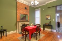 a dining room with green walls and wood flooring has a red table cloth on it