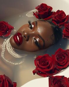 a woman is floating in a tub with red roses all around her and eyes closed