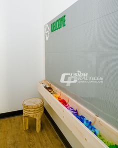 a wooden bench sitting next to a wall filled with colorful candies and a stool