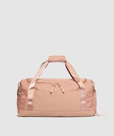 a pink duffel bag with straps and handles on the front, sitting against a white background