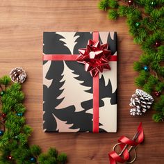 a present wrapped in black and white wrapping paper with red ribbon next to christmas decorations