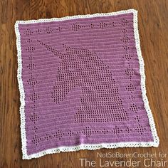 a purple crocheted blanket sitting on top of a wooden floor next to a table