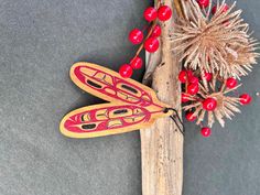 a red and black wooden dragonfly sitting on top of a piece of wood