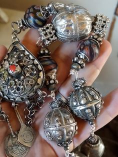 An assemblage of Yemen wedding globe beads, one is hallmarked, and a pear shaped fibula pendant from Siouan Ouan region in Morocco. These are rare hard to find silver pendants. The central stone I think is not real coral. It has three original silver and niello charm pendants on original chains, one was missing, so I've added a Berber silver evil eye charm. Handmade chain using sterling wire with Yemen berry beads, (silver content unknown), faceted pyrite, silver beads from India, silver plated Spiritual Teardrop Jewelry For Jewelry Making, Traditional Silver Teardrop Necklace, Ornate Silver Teardrop Necklace, Traditional Sterling Silver Teardrop Pendant Jewelry, Traditional Sterling Silver Teardrop Pendant Necklace, Ornate Silver Teardrop Pendant Jewelry, Ceremonial Silver Dangle Jewelry, Unique Ceremonial Jewelry With Silver Beads, Unique Antique Silver Jewelry With Silver Beads