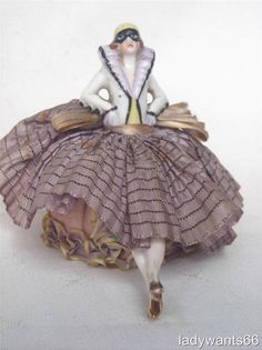 a figurine sitting on top of a pile of books wearing a dress and hat