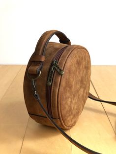 "This crossbody bag is made of high quality vegan leather in brown. It has a circular shape. It is lightweight but durable. It has a rustic, distressed look. It has an adjustable and detachable long strap and a top handle. It is unlined. It can be used as crossbody or clutch. You can see the color options in the last photo. Measurements: Height: 7\" - 18 cm Depth: 3.2\" - 8 cm Detachable strap length: Max 48\" - 124 cm IMPORTANT! Your orders between 7-25 August will be shipped on August 28. Deli Round Leather Bag, Brown Shoulder Bag With Adjustable Strap And Round Handle, Brown Round Case Shoulder Bag For Travel, Brown Round Case Bag With Detachable Strap, Brown Round Case Shoulder Bag For Everyday, Brown Round Case Shoulder Bag, Leather Circle Bag, Round Crossbody Bag, Round Purse